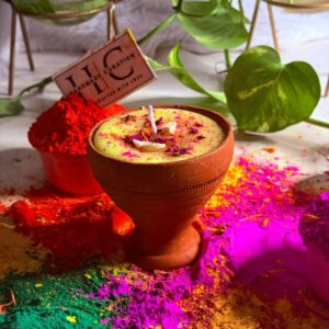 Luxury Holi thandai soy wax candle surrounded by vibrant gulal colors