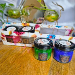 Set of colorful 25gm mini jar candles in red, white, green, blue, and purple displayed on a wooden base, perfect for home decor and gifting