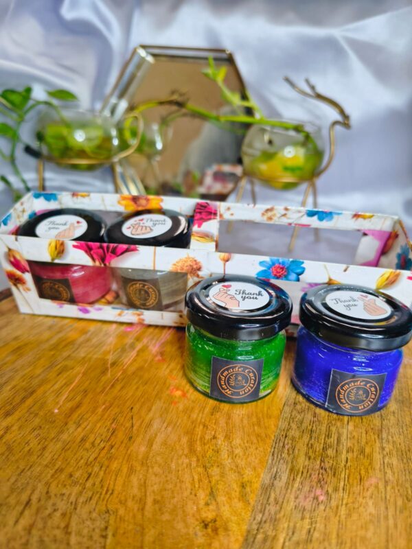 Set of colorful 25gm mini jar candles in red, white, green, blue, and purple displayed on a wooden base, perfect for home decor and gifting