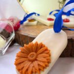 Handcrafted floral wax sachets with blue ribbons displayed on a wooden tray