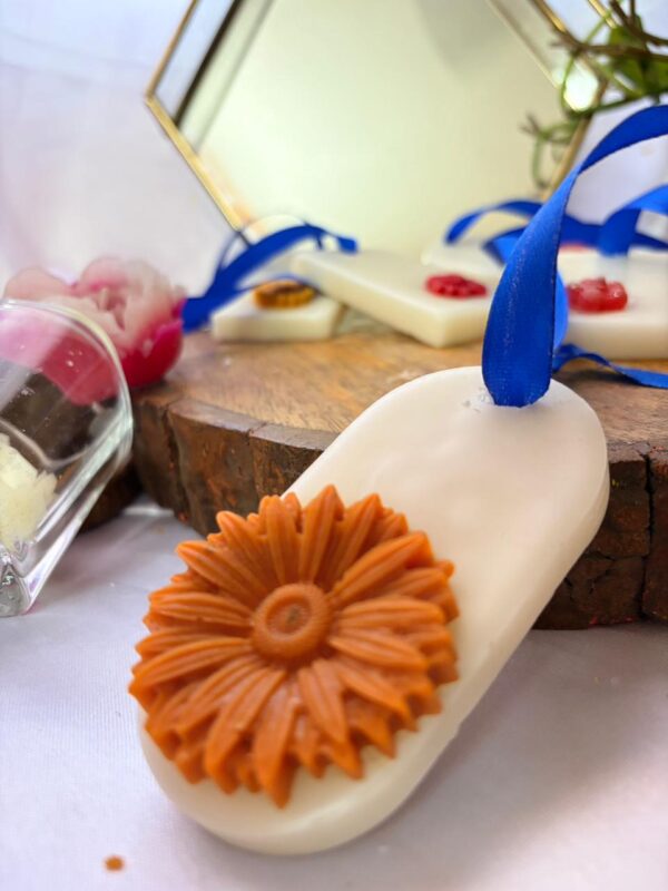 Handcrafted floral wax sachets with blue ribbons displayed on a wooden tray